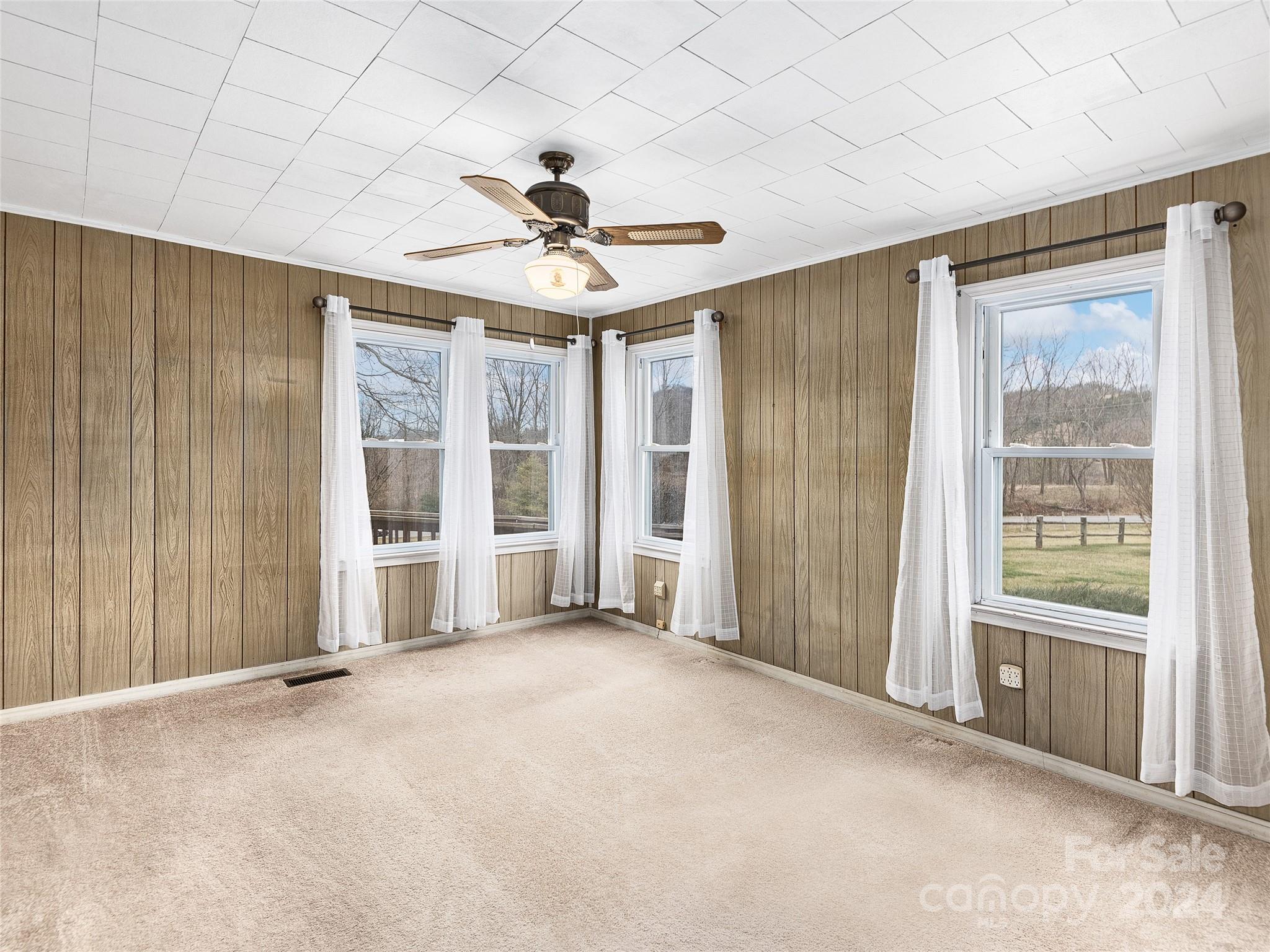 704 Mulberry Street Clyde, NC 28721 - Photo 12 of 36 an empty room with chandelier fan and windows