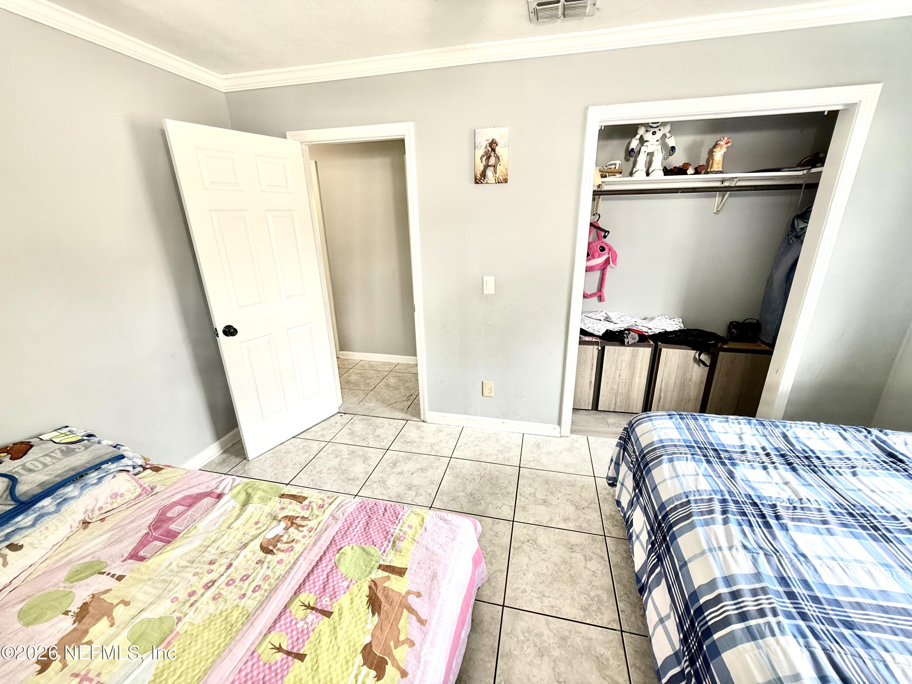 10162 Herndon Road Jacksonville, FL 32246 - Photo 14 of 31 a bed sitting in a bedroom next to a window