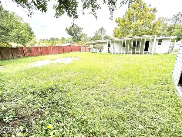 a view of a house with a big yard and large trees