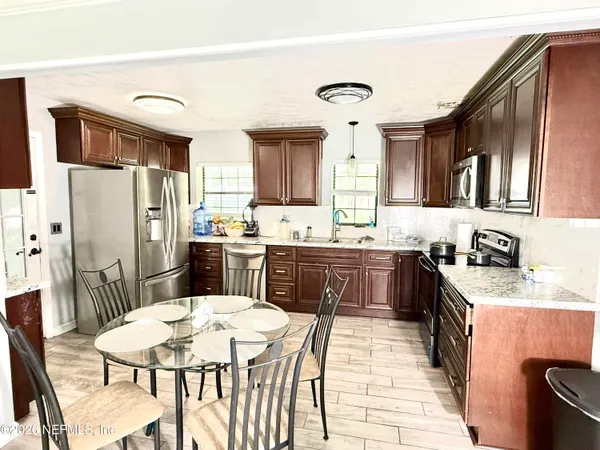 a kitchen with stainless steel appliances granite countertop a refrigerator a stove a sink a dining table and chairs