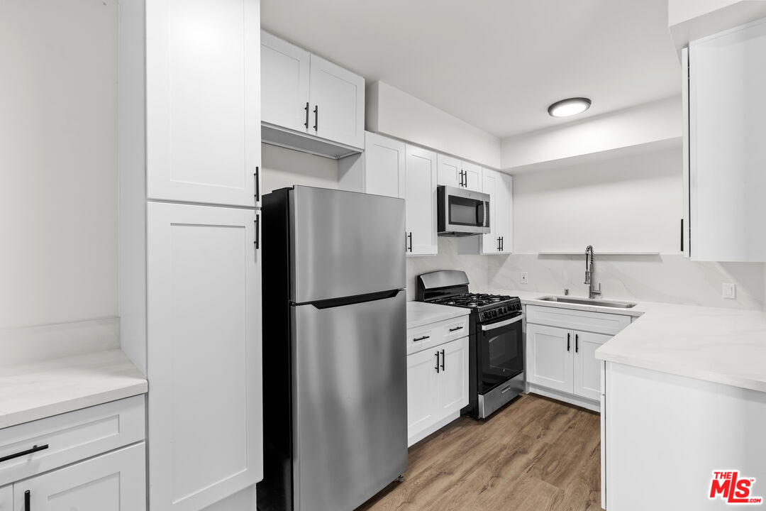 7825 West Manchester Avenue, Unit 6 Playa del Rey, CA 90293 - Photo 6 of 11 a kitchen with a refrigerator a stove top oven and cabinets