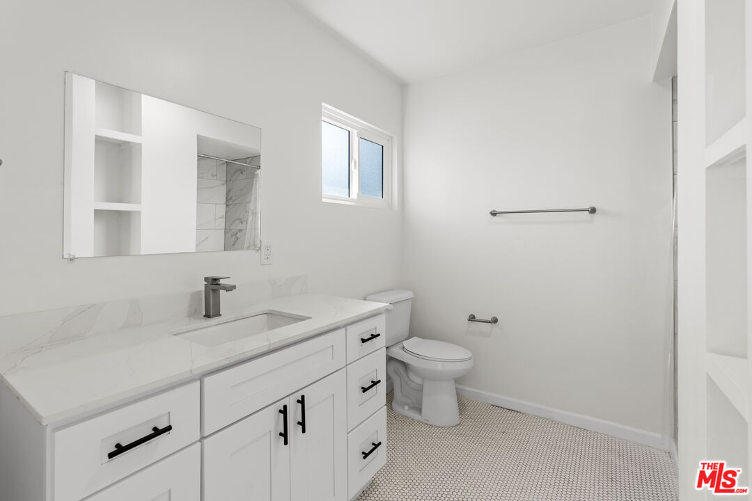 7825 West Manchester Avenue, Unit 6 Playa del Rey, CA 90293 - Photo 8 of 11 a bathroom with a granite countertop toilet a sink and a mirror