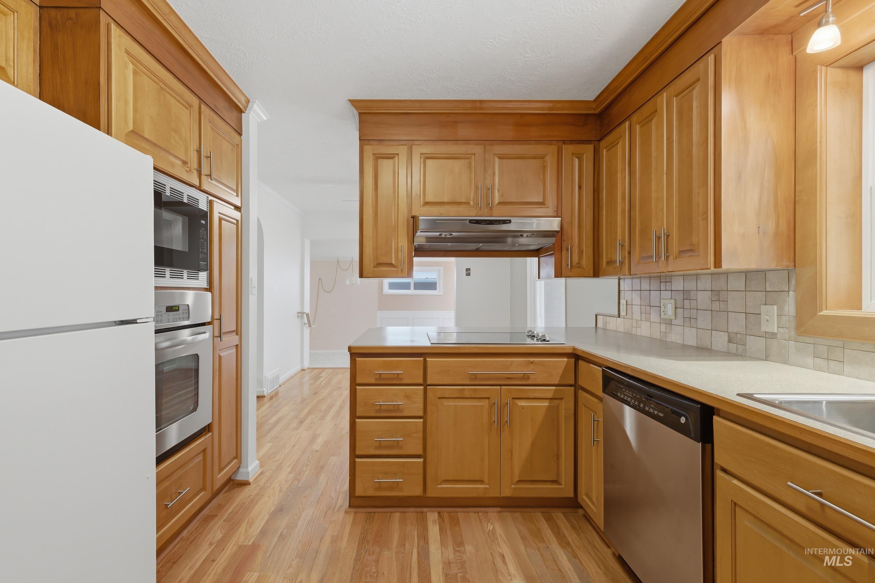 504 West Howe Street Boise, ID 83706 - Photo 23 of 47 Kitchen featuring wood-finish cabinetry, stainless steel appliances, a built-in oven and microwave, and a tile backsplash