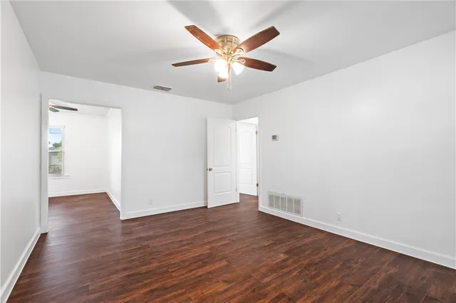 an empty room with wooden floor and ceiling fan