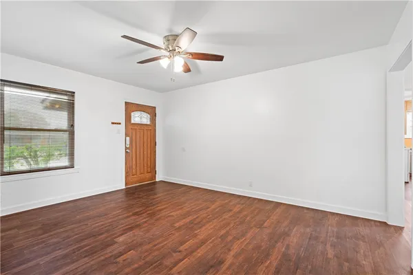 a view of an empty room with wooden floor and a window