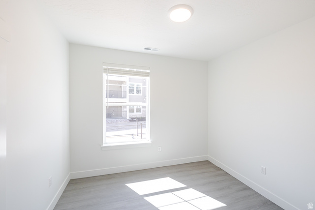 4664 South 680th West, Unit S102 Mapleton, UT 84664 - Photo 6 of 16 Bright room featuring a single window with blinds, wood-finish flooring, white baseboards, and a flush-mount ceiling light fixture