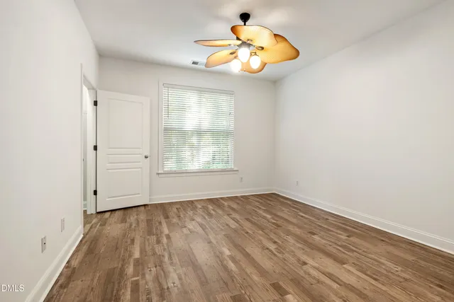 an empty room with wooden floor cabinet and windows