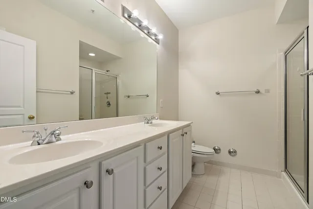 a spacious bathroom with a double vanity sink toilet and a mirror