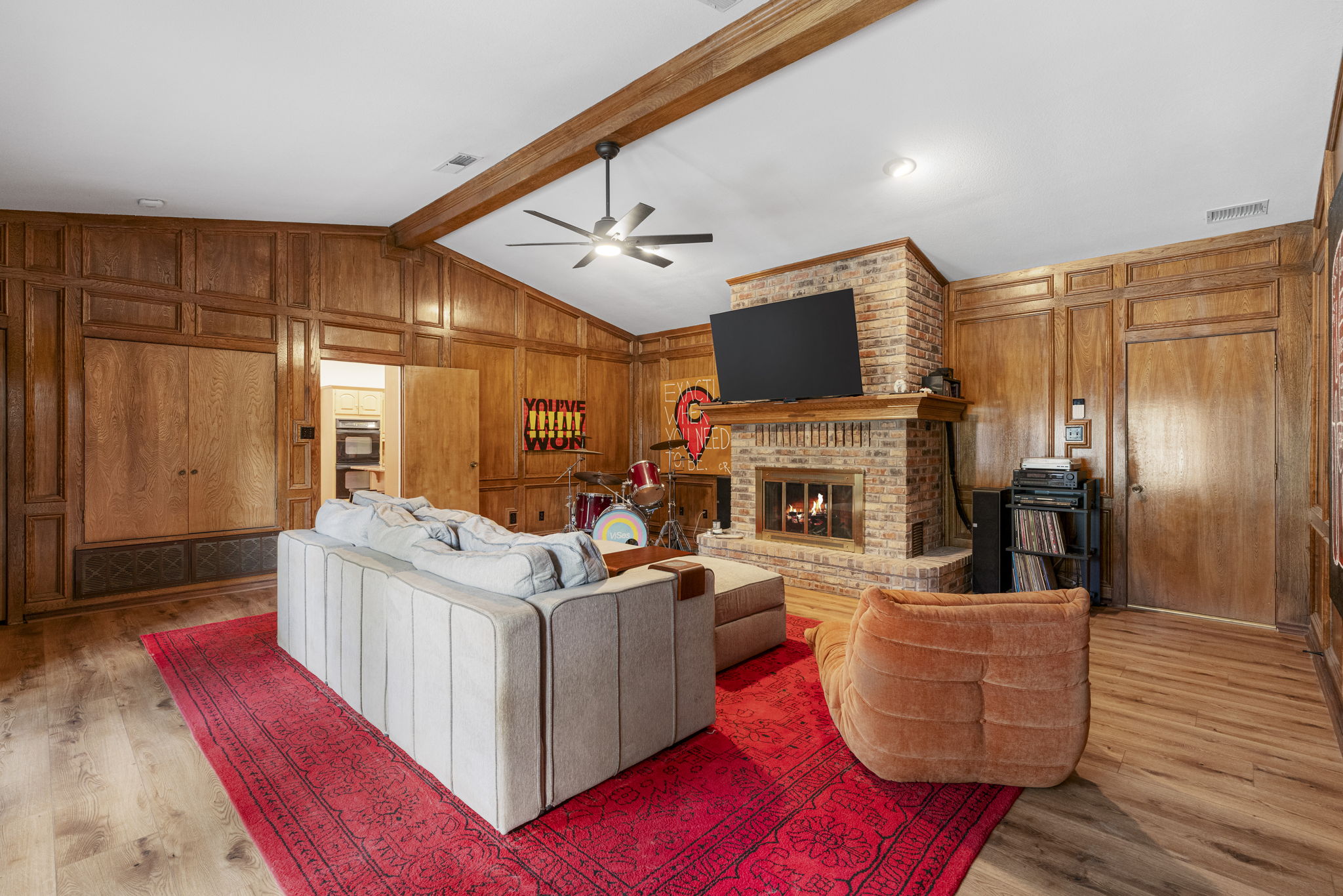 400 Hackberry Street Lockhart, TX 78644 - Photo 8 of 40 A warm and inviting living room boasts wood paneled walls, a brick fireplace, and gleaming hardwood floors.
