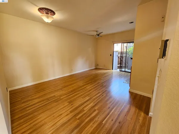 a view of an empty room with wooden floor and a window