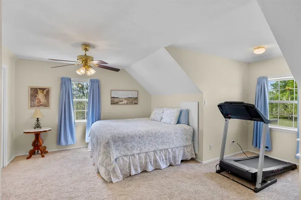 a bedroom with a bed chandelier painting on the wall and a large window