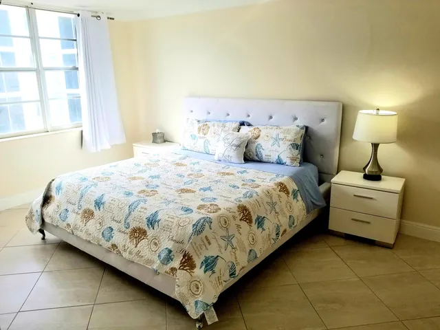 a large bed sitting in a bedroom next to a lamp with a lamp and a large window