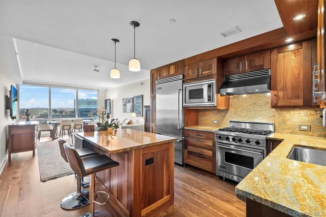 a kitchen with stainless steel appliances granite countertop a stove a sink dishwasher a dining table and chairs with wooden floor