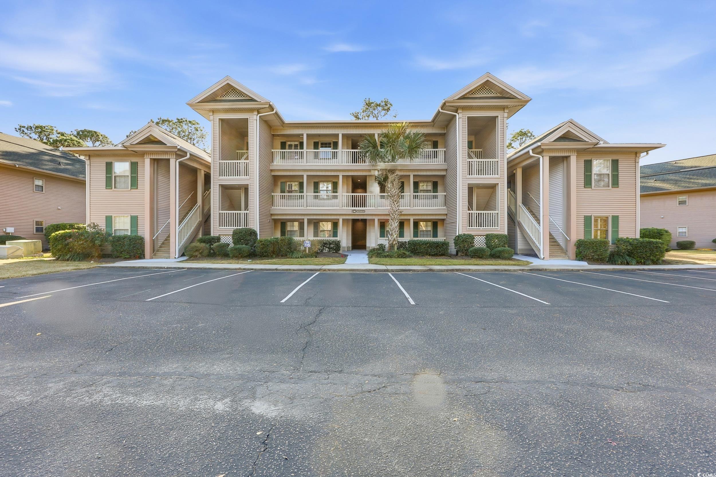 View of apartment building / complex featuring stairs and uncovered parking