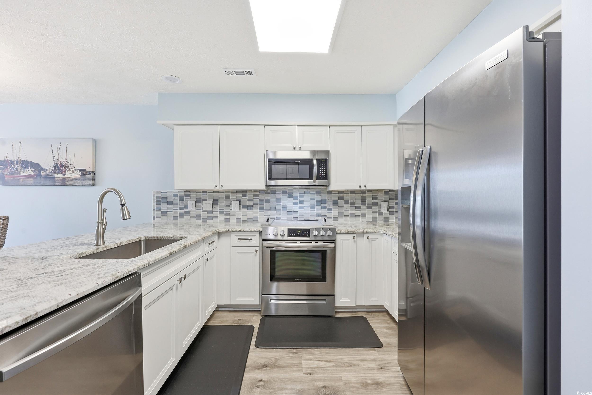 448 Pinehurst Lane, Unit 16F Pawleys Island, SC 29585 - Photo 9 of 31 Kitchen featuring appliances with stainless steel finishes, light stone counters, and white cabinetry