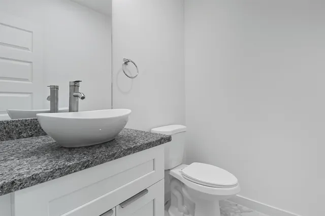 a bathroom with a granite countertop toilet a sink and mirror
