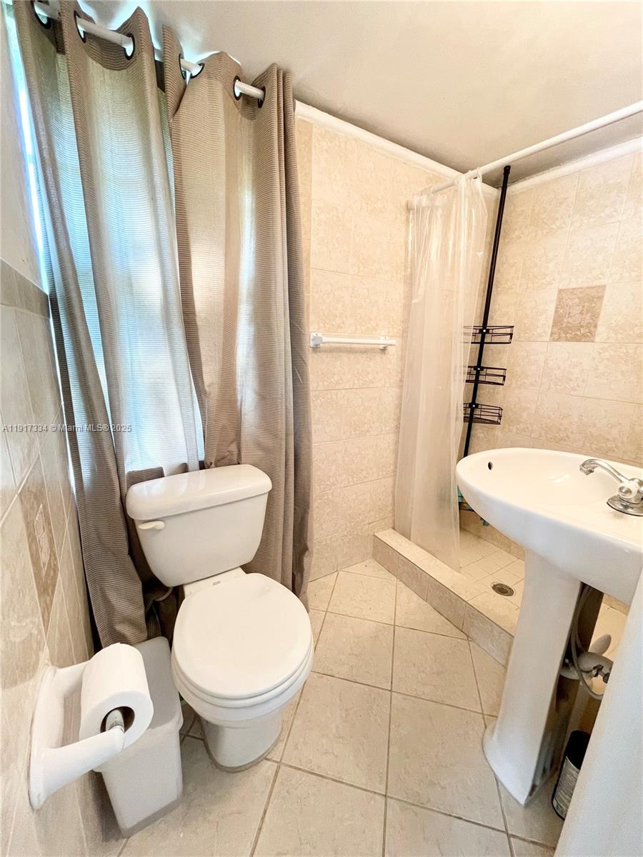 3085 Elizabeth Street, Unit 2 Miami, FL 33133 - Photo 9 of 18 a white toilet sitting next to a bathroom sink and a shower