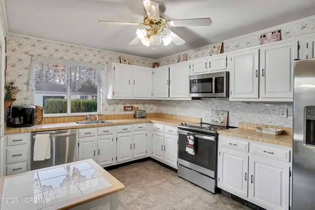 a kitchen with stainless steel appliances granite countertop a refrigerator a stove and white cabinets