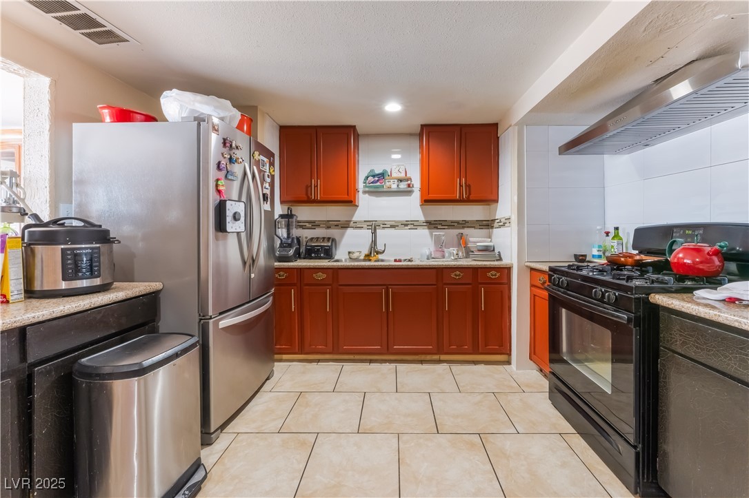 1908 Ardmore Street Las Vegas, NV 89104 - Photo 13 of 29 Kitchen featuring black gas range, light countertops, stainless steel refrigerator with ice dispenser, light tile patterned flooring, and tasteful backsplash