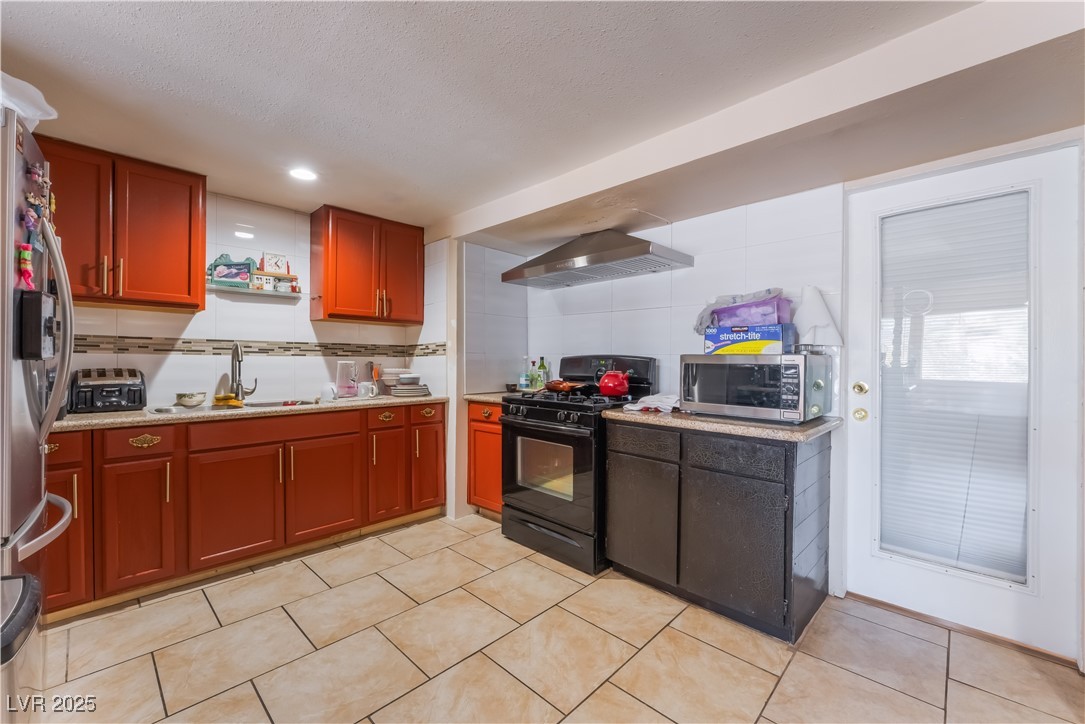 1908 Ardmore Street Las Vegas, NV 89104 - Photo 14 of 29 Kitchen with stainless steel appliances, wall chimney range hood, light countertops, light tile patterned flooring, and recessed lighting