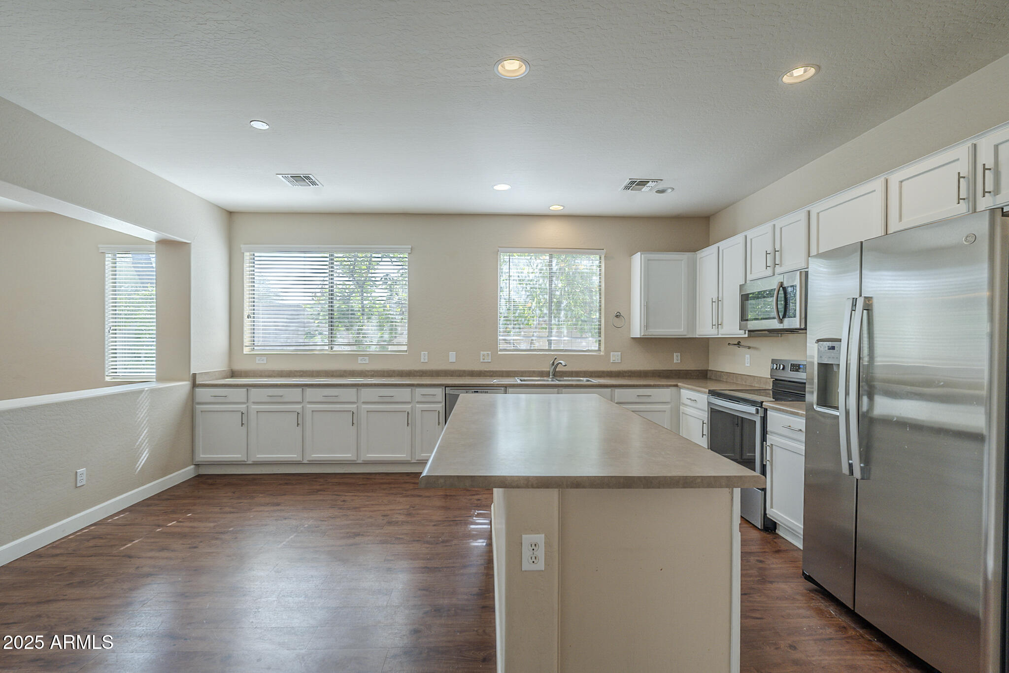 15902 West Hearn Road Surprise, AZ 85379 - Photo 38 of 73 a kitchen with kitchen island a large window cabinets and stainless steel appliances