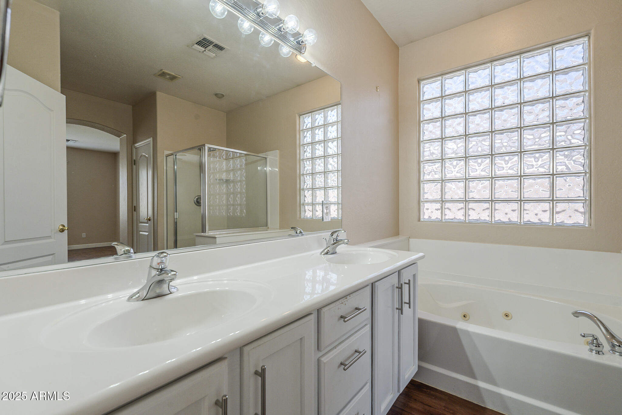 15902 West Hearn Road Surprise, AZ 85379 - Photo 49 of 73 a bathroom with a double vanity sink large mirror and a bathtub
