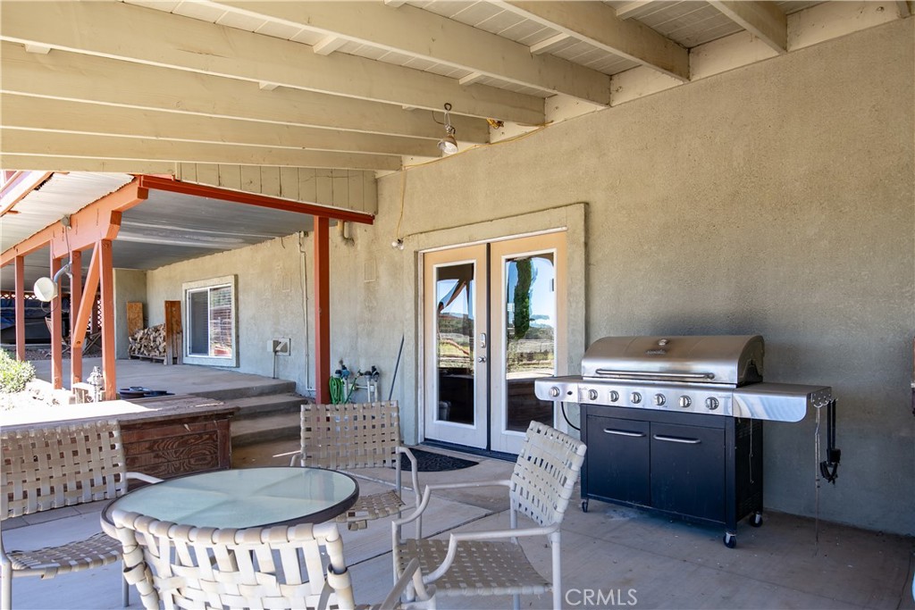 10960 Steinhoff Road Frazier Park, CA 93225 - Photo 19 of 46 A welcoming ground-level perspective of the home's shaded outdoor living space. This covered concrete patio includes a cozy seating and dining layout, a premium stainless steel barbecue grill, and elegant French doors that seamlessly connect the indoor and outdoor entertaining areas.
