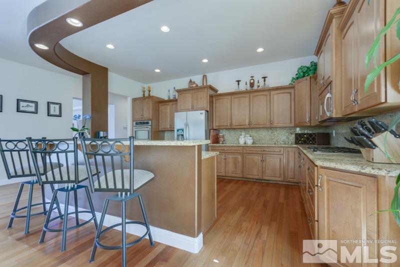 12670 Silver Wolf Road Reno, NV 89511 - Photo 10 of 25 a kitchen with kitchen island granite countertop wooden floors and white cabinets
