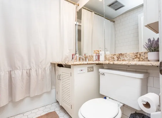 a bathroom with a sink a toilet a mirror and shower curtain