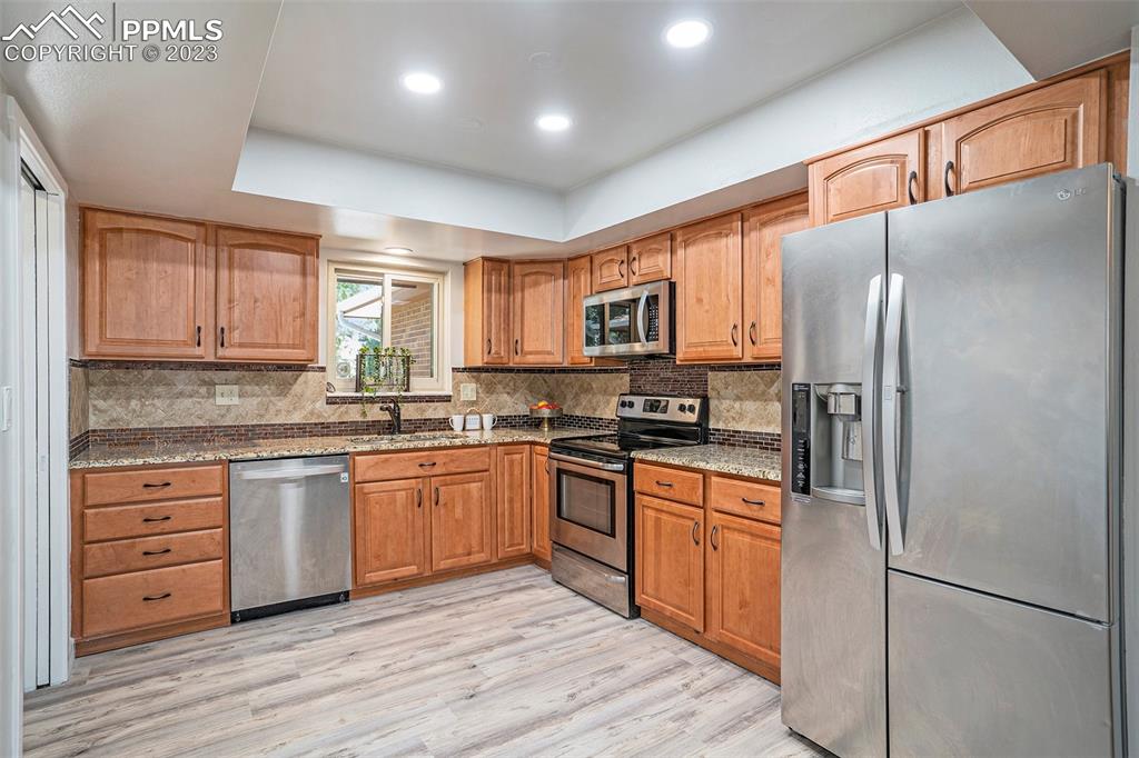 4506 Ridgecrest Drive Colorado Springs, CO 80918 - Photo 8 of 29 a kitchen with stainless steel appliances granite countertop a refrigerator a sink dishwasher a stove top oven a refrigerator with island and cabinets
