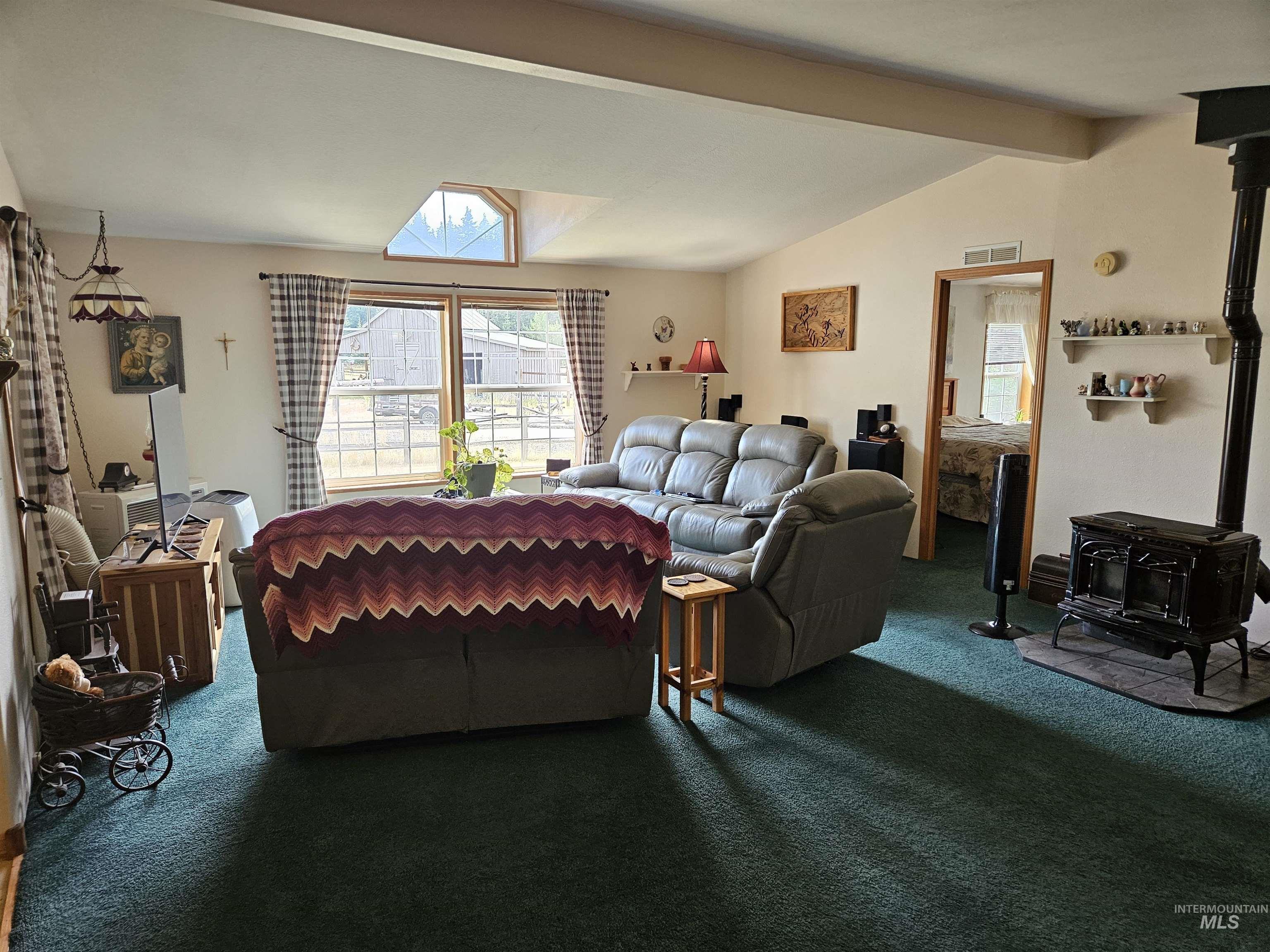 232 Lackey Road Weippe, ID 83553 - Photo 2 of 33 Living room featuring a wood stove and dark carpet
