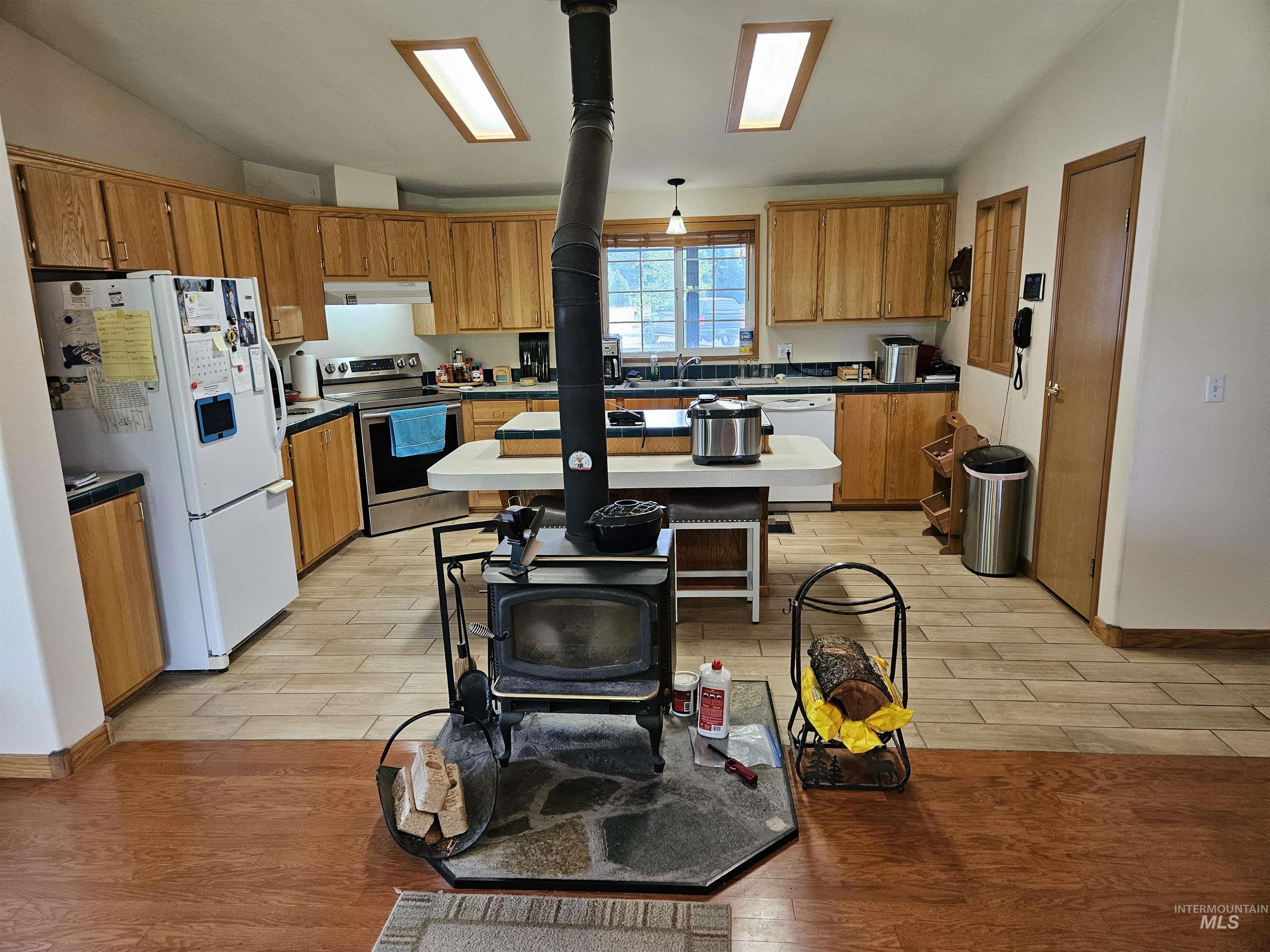 232 Lackey Road Weippe, ID 83553 - Photo 5 of 33 Kitchen with vaulted ceiling, light wood-type flooring, white appliances, and brown cabinetry