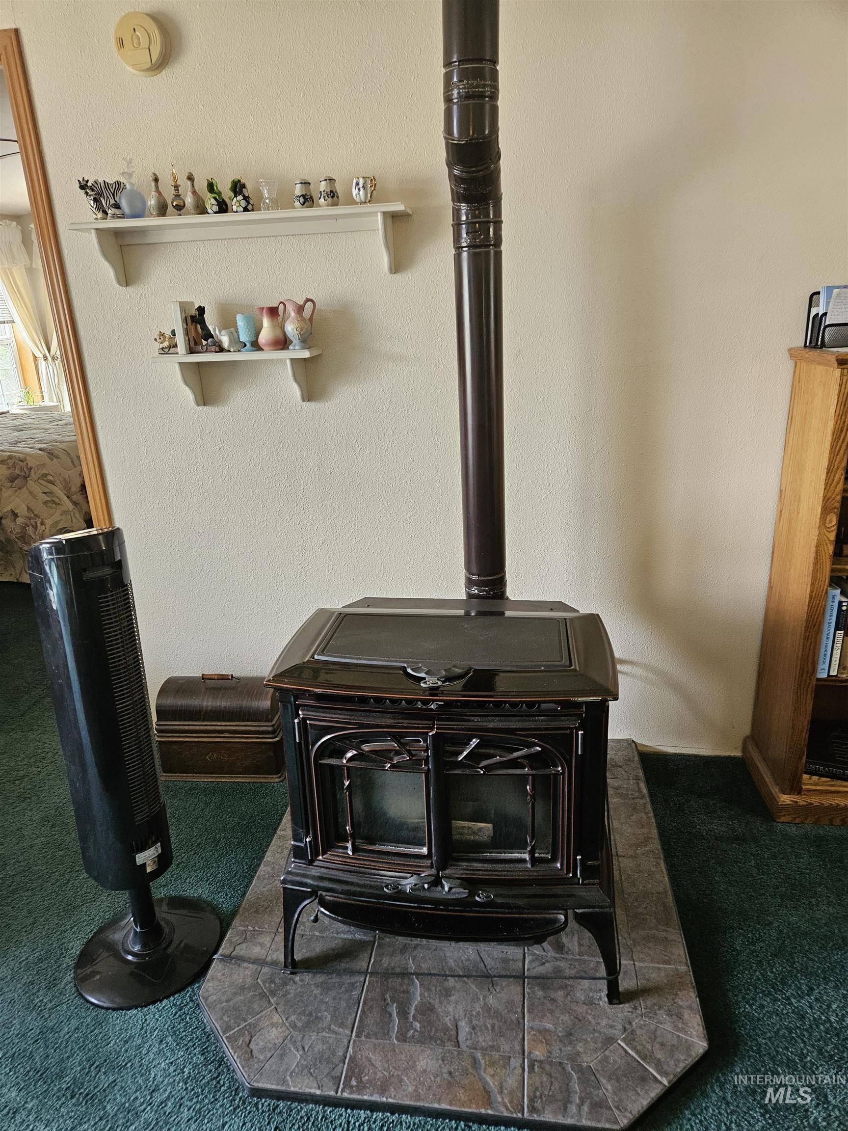 232 Lackey Road Weippe, ID 83553 - Photo 8 of 33 Detailed view of a wood stove, carpet, a textured wall, and a smoke detector