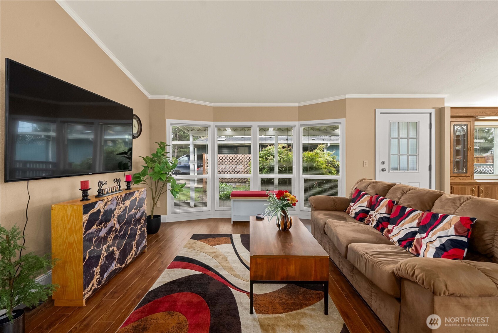 836 Harman Way South, Unit 62 Orting, WA 98360 - Photo 5 of 40 a living room with furniture a flat screen tv and a floor to ceiling window