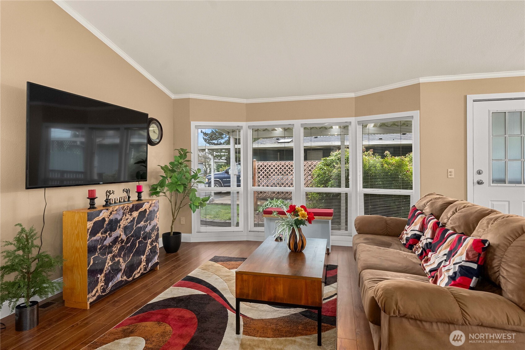 836 Harman Way South, Unit 62 Orting, WA 98360 - Photo 6 of 40 a living room with furniture a flat screen tv and a floor to ceiling window