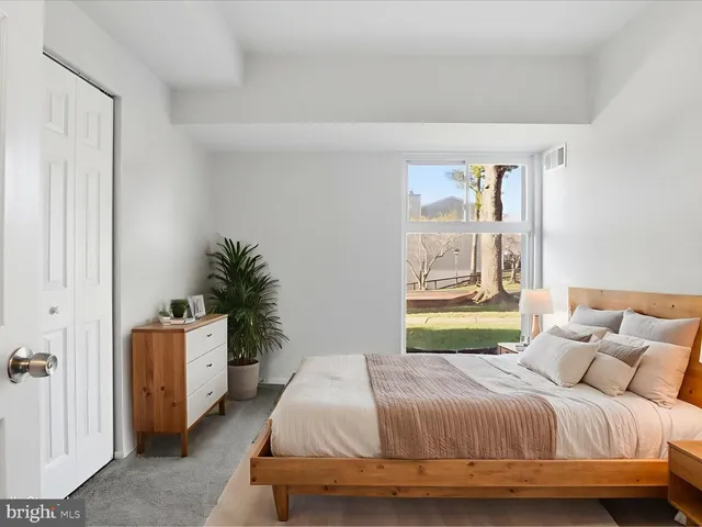 a bedroom with a bed and a potted plant next to a window