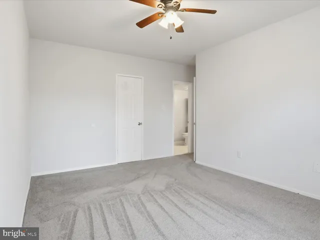 an empty room with a chandelier fan and wooden floor