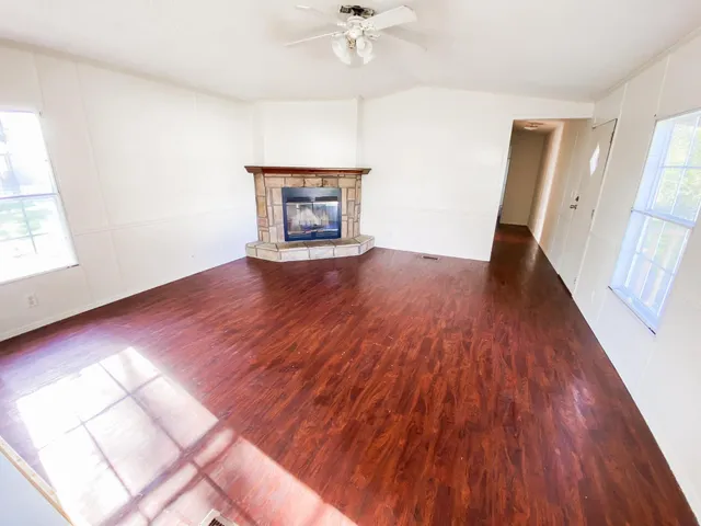 an empty room with wooden floor a fireplace and windows