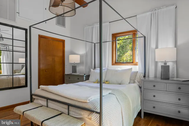 a bedroom with a bed a mirror on dresser and a window