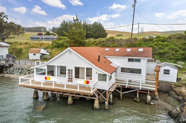 a white house sitting next to a yard with a table and chairs