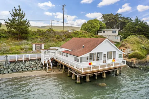 a white house with a large pool and lawn chairs under an umbrella