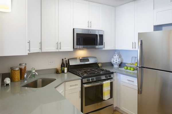 a kitchen with stainless steel appliances a stove a refrigerator a sink a stove and white cabinets