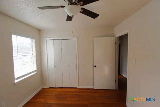 a view of empty room with wooden floor and fan