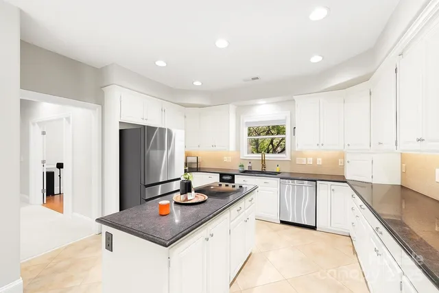 a kitchen with stainless steel appliances granite countertop a sink refrigerator and cabinets