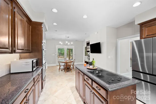 a living room with stainless steel appliances furniture and a kitchen view