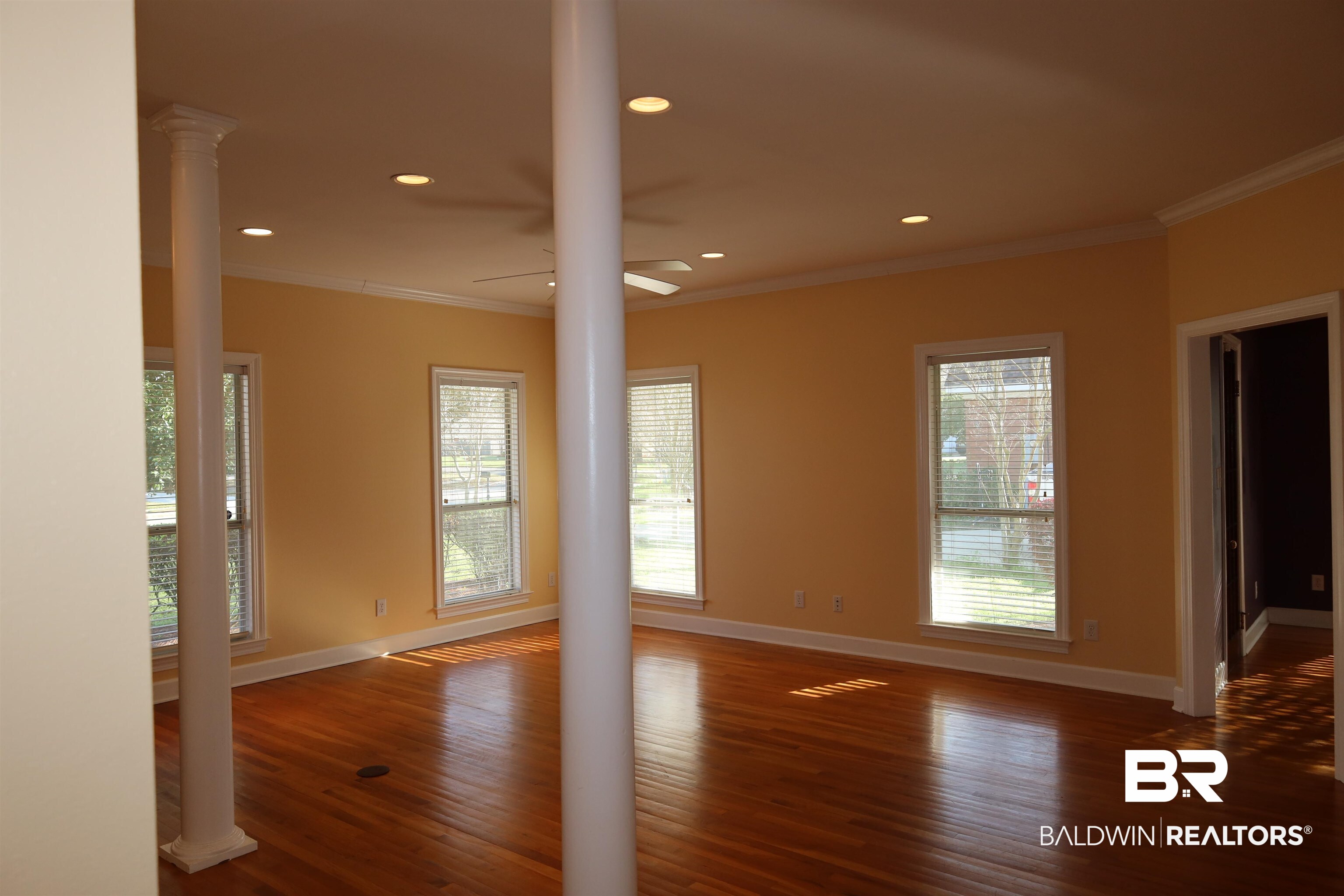 111 Destrehan Road Fairhope, AL 36532 - Photo 2 of 29 Empty room featuring a ceiling fan, wood finished floors, baseboards, decorative columns, and ornamental molding