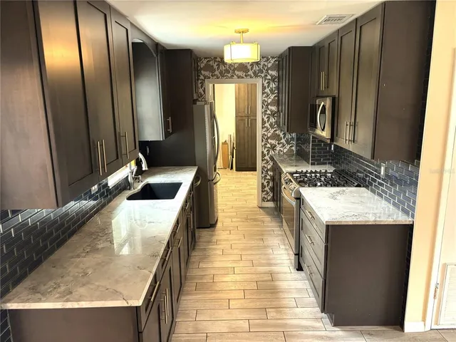 a kitchen with stainless steel appliances granite countertop a stove a sink and a refrigerator