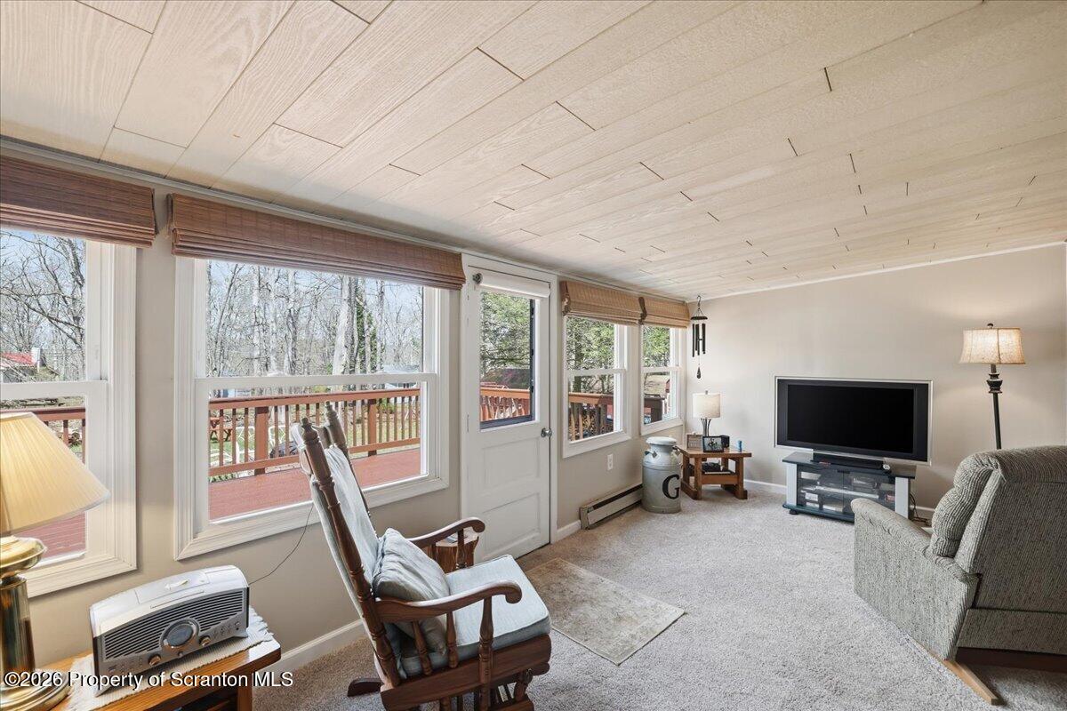 113 Stoney Hill Road Dingmans Ferry, PA 18328 - Photo 25 of 65 a living room with furniture a flat screen tv and a floor to ceiling window