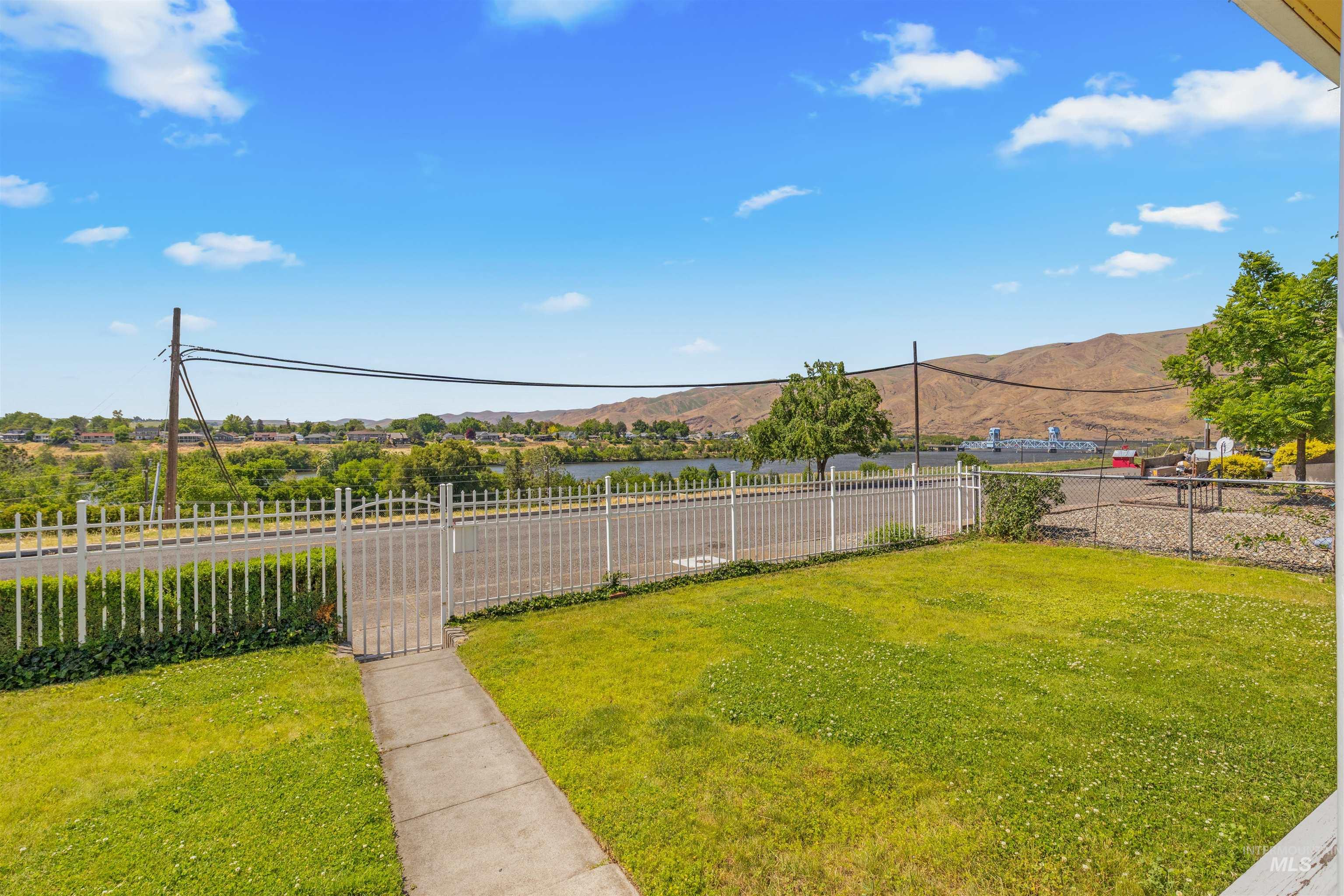 619 Prospect Avenue Lewiston, ID 83501 - Photo 27 of 37 Front lawn with a white picket fence and gate, a concrete walkway, and a distant body of water