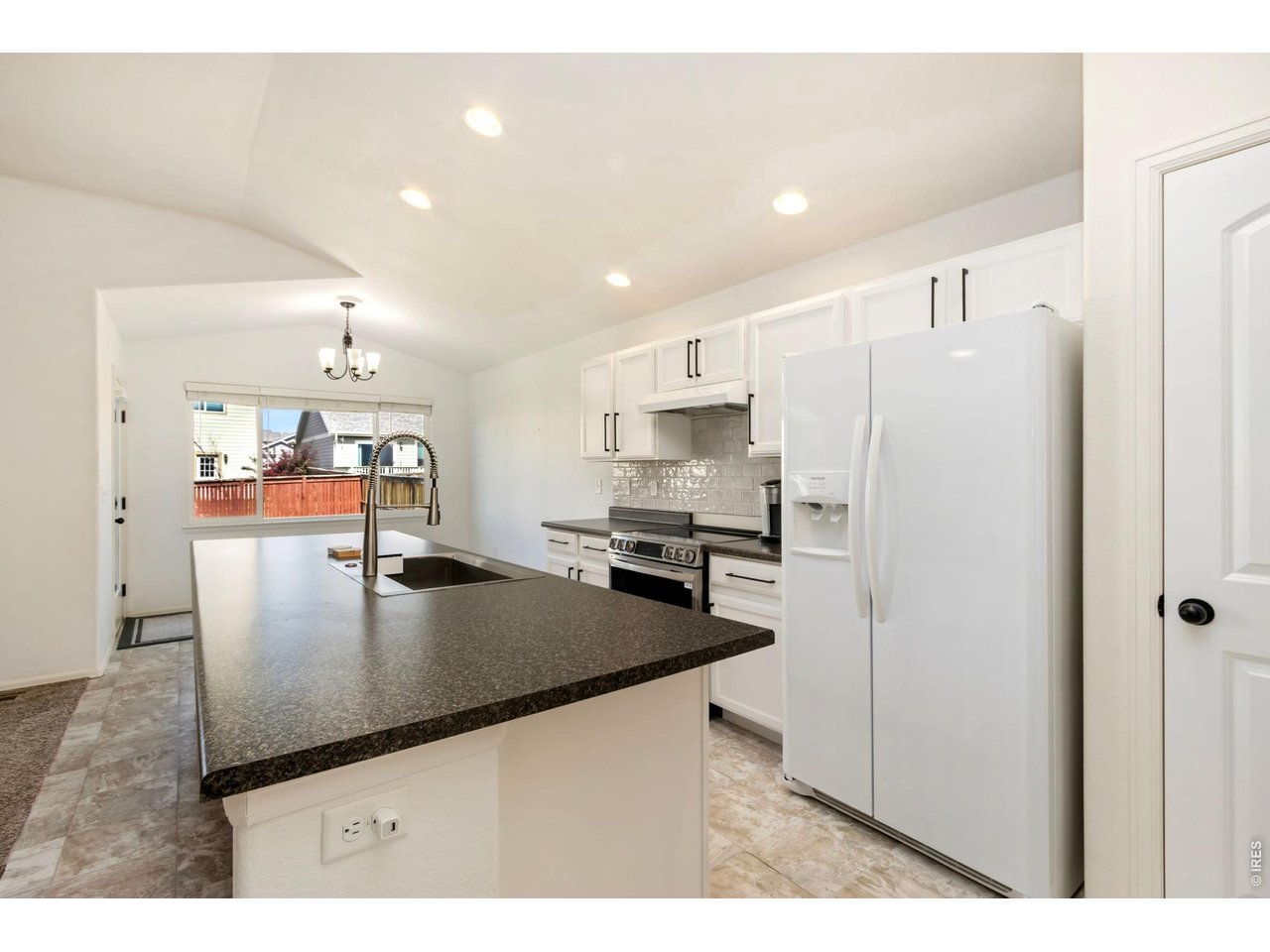 1484 First Light Drive Windsor, CO 80550 - Photo 7 of 23 a kitchen with stainless steel appliances granite countertop a refrigerator a stove a sink a microwave and white cabinets with wooden floor